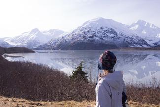 A visitor views mountain reflections on a still Portage lake in March 2015.
